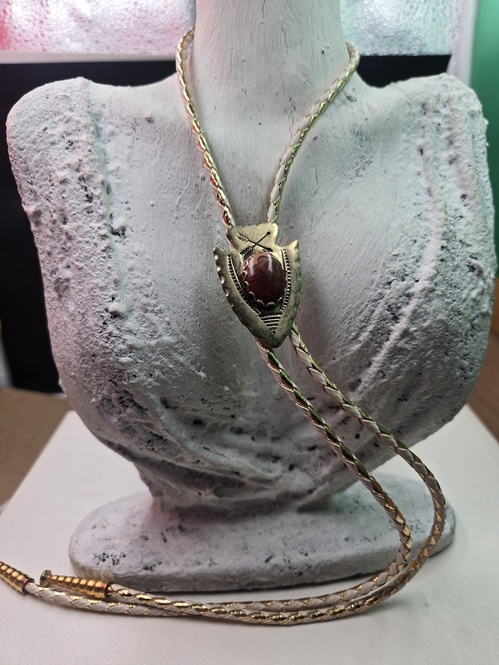 vintage gold-toned arrowhead bolo tie featuring a central red agate-style stone
